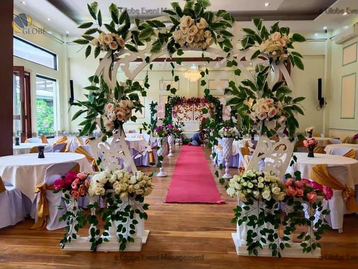 Professionally organized corporate seminar with stage and seating arrangements. Stylish product launch event setup with lights and branded backdrops. Corporate gala dinner with elegant table decor and ambient lighting. Annual day event with large LED screens and stunning stage setup. Beautifully arranged outdoor seating for a private party event. Event management team setting up a large stage for a gala night. Stunning decor featuring floral arches and chandeliers for an event. Table setup with elegant glassware and centerpiece for a formal event. Stunning flower decoration for a grand wedding entrance. Outdoor event lighting with string lights and lanterns creating a magical ambiance. Creative flower arrangement for a corporate event stage. Romantic candlelight decor with floral centerpieces for a party.