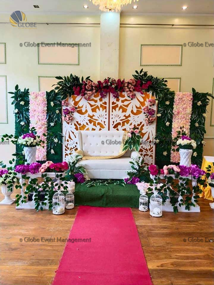 Professionally organized corporate seminar with stage and seating arrangements. Stylish product launch event setup with lights and branded backdrops. Corporate gala dinner with elegant table decor and ambient lighting. Annual day event with large LED screens and stunning stage setup. Beautifully arranged outdoor seating for a private party event. Event management team setting up a large stage for a gala night. Stunning decor featuring floral arches and chandeliers for an event. Table setup with elegant glassware and centerpiece for a formal event. Stunning flower decoration for a grand wedding entrance. Outdoor event lighting with string lights and lanterns creating a magical ambiance. Creative flower arrangement for a corporate event stage. Romantic candlelight decor with floral centerpieces for a party.