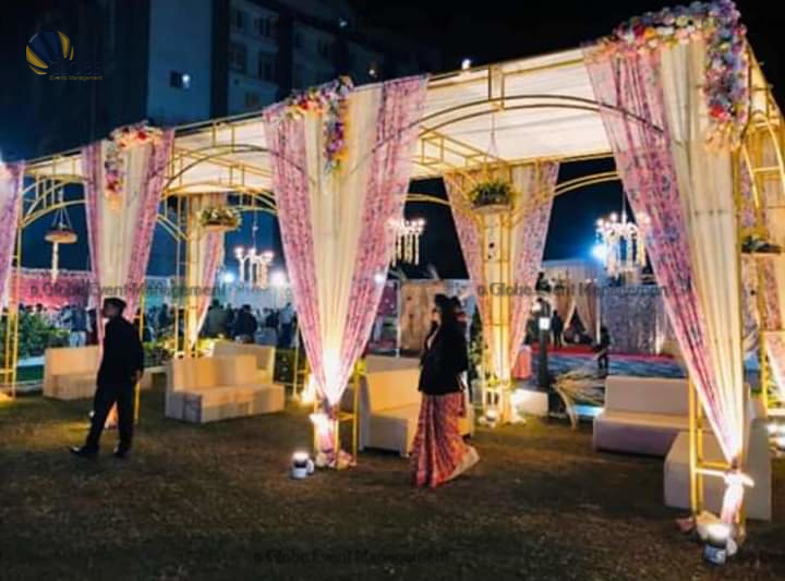 Professionally organized corporate seminar with stage and seating arrangements. Stylish product launch event setup with lights and branded backdrops. Corporate gala dinner with elegant table decor and ambient lighting. Annual day event with large LED screens and stunning stage setup. Beautifully arranged outdoor seating for a private party event. Event management team setting up a large stage for a gala night. Stunning decor featuring floral arches and chandeliers for an event. Table setup with elegant glassware and centerpiece for a formal event. Stunning flower decoration for a grand wedding entrance. Outdoor event lighting with string lights and lanterns creating a magical ambiance. Creative flower arrangement for a corporate event stage. Romantic candlelight decor with floral centerpieces for a party.