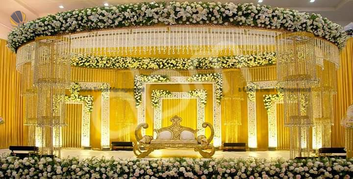 Professionally organized corporate seminar with stage and seating arrangements. Stylish product launch event setup with lights and branded backdrops. Corporate gala dinner with elegant table decor and ambient lighting. Annual day event with large LED screens and stunning stage setup. Beautifully arranged outdoor seating for a private party event. Event management team setting up a large stage for a gala night. Stunning decor featuring floral arches and chandeliers for an event. Table setup with elegant glassware and centerpiece for a formal event. Stunning flower decoration for a grand wedding entrance. Outdoor event lighting with string lights and lanterns creating a magical ambiance. Creative flower arrangement for a corporate event stage. Romantic candlelight decor with floral centerpieces for a party. Wedding Planners in Bangalore