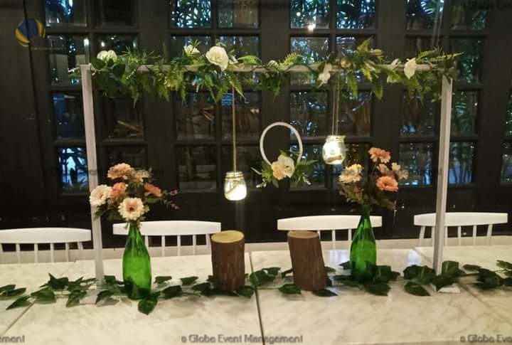 Professionally organized corporate seminar with stage and seating arrangements. Stylish product launch event setup with lights and branded backdrops. Corporate gala dinner with elegant table decor and ambient lighting. Annual day event with large LED screens and stunning stage setup. Beautifully arranged outdoor seating for a private party event. Event management team setting up a large stage for a gala night. Stunning decor featuring floral arches and chandeliers for an event. Table setup with elegant glassware and centerpiece for a formal event. Stunning flower decoration for a grand wedding entrance. Outdoor event lighting with string lights and lanterns creating a magical ambiance. Creative flower arrangement for a corporate event stage. Romantic candlelight decor with floral centerpieces for a party.